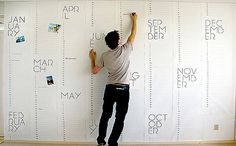 a man standing on top of a wooden floor next to a wall covered in letters