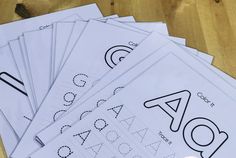 a pile of alphabet practice sheets sitting on top of a wooden table