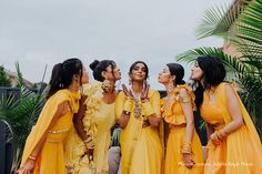 a group of women in yellow dresses standing next to each other with their hands together