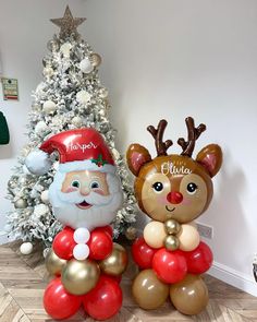 two inflatable reindeers sitting next to a christmas tree with balloons on it