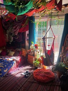 a bedroom with hammock hanging from the ceiling and colorful curtains on the windowsill