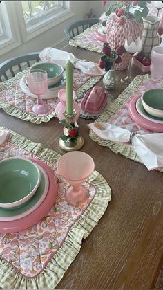 the table is set with pink and green dishes