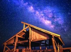 a wooden structure under the night sky filled with stars