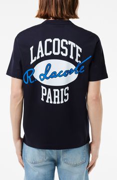 a man wearing a black lacoste t - shirt with blue writing on it