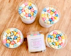 four small glass cups filled with marshmallows on top of a wooden table