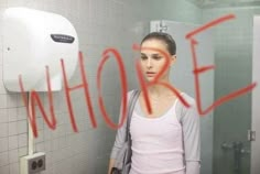 a woman standing in front of a urinal with the word hole painted on it