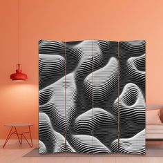 a room divider with black and white designs on the side, in front of an orange wall