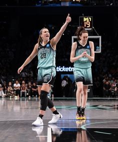 two women in green uniforms playing basketball on a court