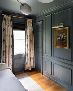 a bedroom with blue walls and wood flooring, painted in farrowe gray