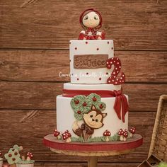 a three tiered cake with a monkey on top and red ribbon around the edges