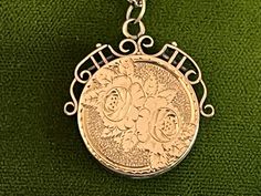 "Description: Beautiful round vintage 10K yellow gold fob locket necklace. This antique fob locket features an etched design of two flowers surrounded by leaves on the front. The background behind the roses is a textured surface. There are etched notches on the outer rim of the rose design all the way round the round locket front. The back side is plain with no etched design. This antique locket has a decorative and ornate scroll openwork frame around the top that goes downward to the mid sectio Victorian Hallmark Jewelry For Memorial, Victorian Memorial Jewelry With Hallmark, Victorian Necklaces With Charms For Anniversary, Victorian Medallion Jewelry With Hallmark, Victorian Charm Necklace For Formal Occasions, Victorian Formal Necklace With Charms, Victorian Style Formal Necklaces With Charms, Victorian Formal Charms Necklace, Ornate Necklace