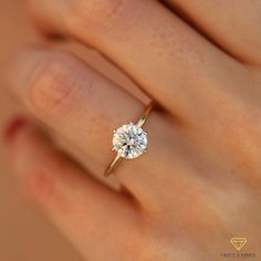 a woman's hand with a diamond ring on top of her finger, showing the center stone