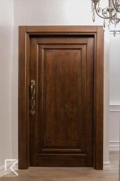 a wooden door with a chandelier hanging from it's side wall in a white room