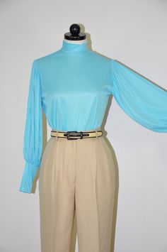 "Gorgeous vintage 1960s - 1970s turquoise blouse with high neckline, zipper back closure, long bishop sleeves with wide cuffs cuffs and slim fit. Super lightweight, soft and silky poly fabric, unlined, sheer. Original tags attached. M E A S U R E M E N T S  (taken flat, unstretched) size on tag: vintage 11-12 / please see measurements below for a perfect fit fits like: approx. XS / S bust (armpit to armpit): 19\" / 48m (x2) waist (at narrowest part): 18\" / 46cm (x2) back (left to right shoulder seam): 14\" / 35.5cm sleeve length (shoulder to cuff): 23\" / 58.5cm length (shoulder to hem): 23\" / 58.5cm fabric: 100% Celanese Fortrel polyester color: blue brand / maker: Cheeky Knits for Lady Manhattan condition: excellent vintage / original tags attached * * * * * * Additional TOPS & SHIRTS: Fitted Turquoise Long Sleeve Tops, Blue Bishop Sleeve Tops For Fall, Blue Fitted Blouse With Balloon Sleeves, Blue Fitted Top With Balloon Sleeves, Retro Blue Blouse For Fall, Fitted Light Blue Blouse For Fall, Turquoise Blouse, Statement Blouse, Bishop Sleeve