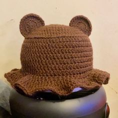 a crocheted bear hat sitting on top of a black pot