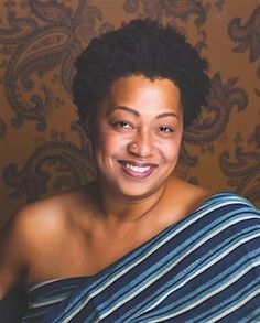 a smiling woman wrapped in a blue and white striped towel, posing for the camera