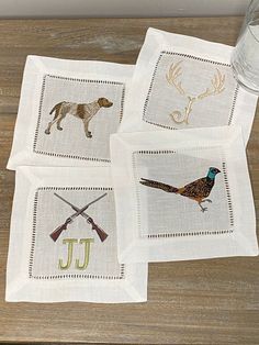 four embroidered napkins with different types of animals on them and the letter j in gold