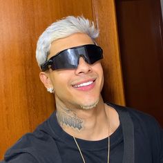 a man with grey hair wearing sunglasses and a black t - shirt smiles at the camera