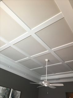 a ceiling fan is hanging from the ceiling in a room with gray walls and white trim