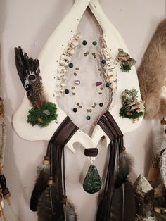 a wall hanging with feathers and beads on it's sides, surrounded by other items