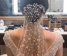 the back of a woman's head wearing a wedding veil with pearls on it