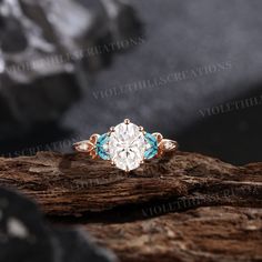 an engagement ring with blue and white stones on top of a piece of drift wood