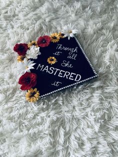 a black graduation cap with flowers on it that says through all she is mastered