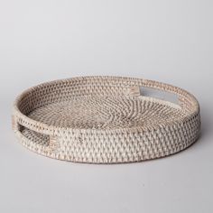 a round woven tray with handles on a white background