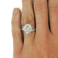 a woman's hand with a diamond ring on top of her finger, showing the center stone