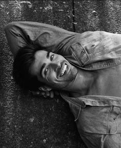 a black and white photo of a man laying on the ground with his eyes closed