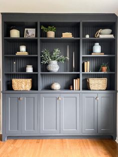 a gray bookcase with baskets and plants on it