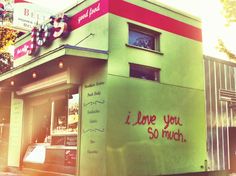 a small green building with graffiti on it's side and the words i love you so much