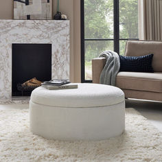 a living room with a white ottoman and fireplace