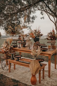 a wooden table topped with vases filled with flowers and food on top of it