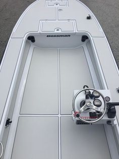 the inside of a white boat with steering wheel and center console on concrete flooring