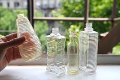 three empty glass bottles sitting on top of a window sill next to each other