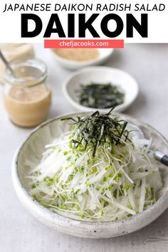 a white bowl filled with shredded greens and seasoning on top of a table next to other dishes