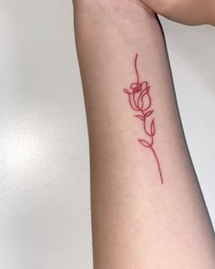 a woman's arm with a tattoo on it that has a red flower in the middle