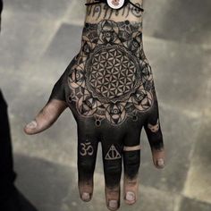 a person's hand with an intricate tattoo on it and some other symbols around the wrist