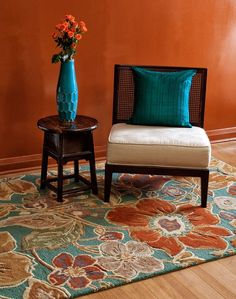 two chairs and a table in front of an orange wall with blue vases on it