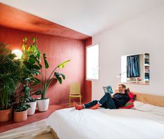 a woman laying on top of a bed next to a potted plant in a bedroom