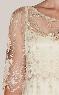 the back of a woman's wedding dress with sheer sleeves and beaded details