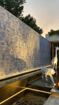 a statue of a giraffe next to a wall with the word dior on it