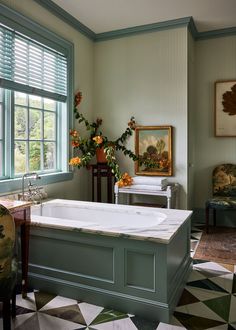 a bath tub sitting in the middle of a room next to a chair and window