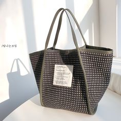 a black and white tote bag sitting on top of a table next to a window