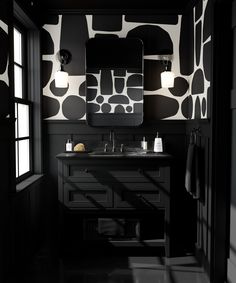 a black and white bathroom with an abstract wallpaper pattern on the walls, two sinks and mirrors