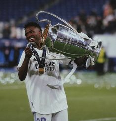 a soccer player holding up a trophy on the field