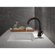 a white sink sitting under a faucet next to a wooden tray with soap