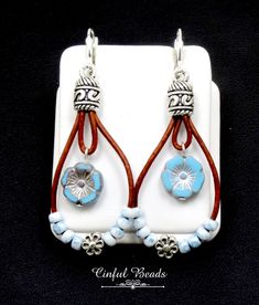 "These charming teardrop boho leather dangle earrings feature a sky blue Czech glass Hawaiian flower bead hanging on distressed natural brown leather cord. Another strand of leather is embellished with marbled blue seed beads surrounding a tibetan style flower bead. The leather has been glued into Tibetan style cord ends. The earrings hang on silver plated brass lever back earwires. The earrings measure 2 1/2\" long from the top of the earwires to the bottom of the longest loop. They are 1\" wid Blue Bohemian Leather Earrings, Bohemian Blue Leather Earrings, Blue Leather Bohemian Earrings, Adjustable Blue Bohemian Teardrop Earrings, Bohemian Light Blue Teardrop Earrings, Handmade Blue Leather Earrings, Boho Leather, Loop Earrings, Hawaiian Flowers