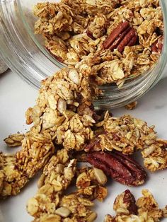 granola in a glass jar with nuts scattered around it